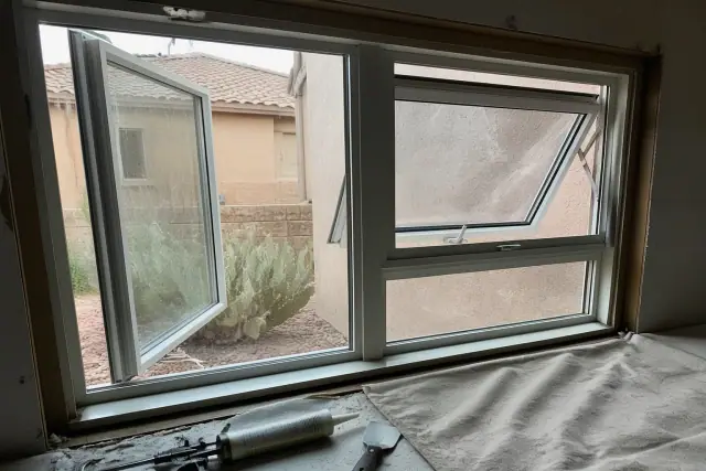Casement and awning window frame installation in a Surprise, AZ home with tools on a drop cloth.