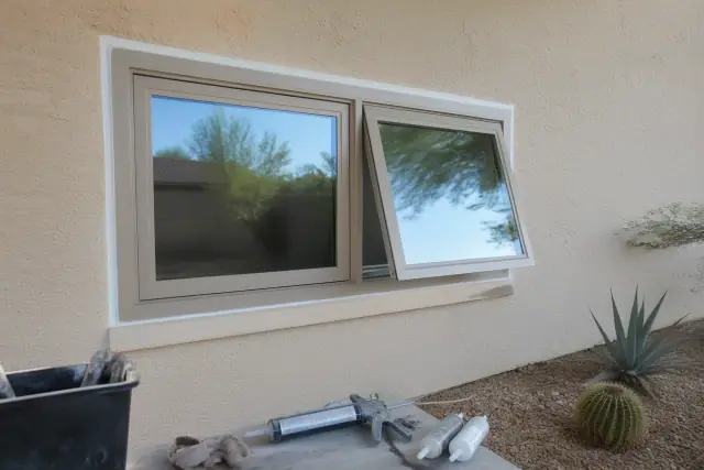 Caulking the exterior frame of a newly installed casement window on a stucco home in Phoenix, AZ.