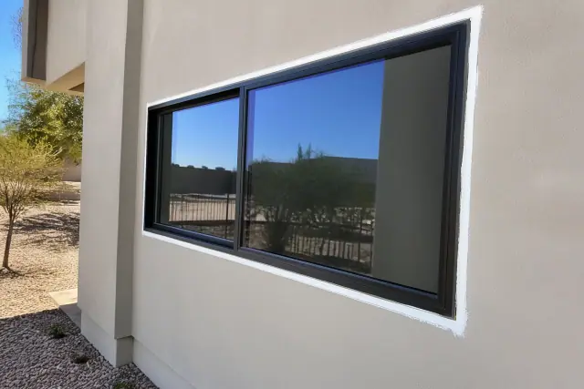 Caulking the exterior frame of a newly installed commercial window at a jobsite in Phoenix, AZ.