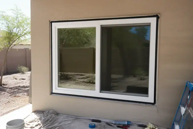 Commercial window installation on a stucco wall with tools on a drop cloth in Gilbert, AZ.