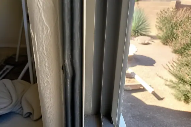 Side-by-side view of a weathered compression seal and metal sliding track at a construction site in Phoenix, AZ.