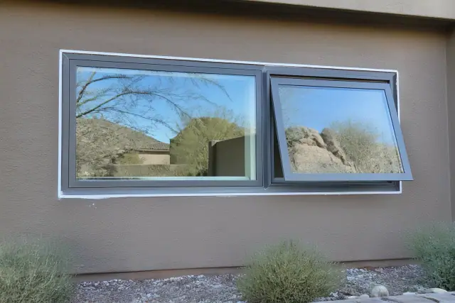 Close-up of a contractor caulking the frame of a new window on a stucco home in Phoenix, AZ.