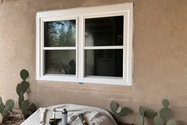 New vinyl window installation with construction tools and prickly pear cacti in the background in Phoenix, AZ.