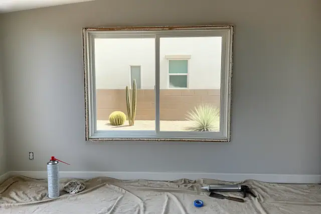 Window frame installation in progress with tools and sealant on a drop cloth at a home in Surprise, AZ.