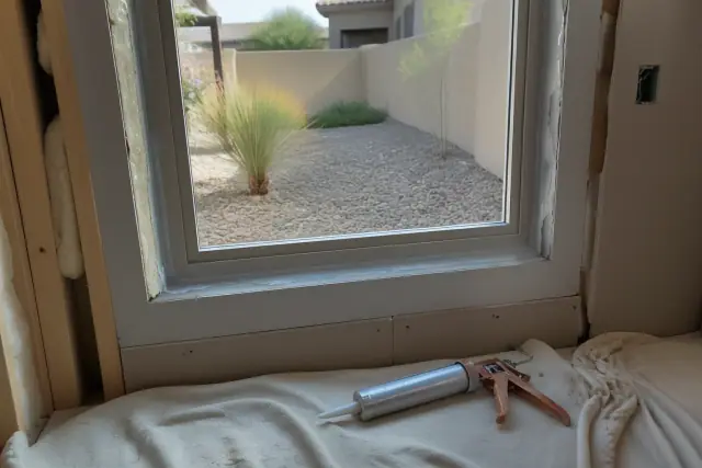 New window frame installation in a residential home in Goodyear, AZ, with tools and sealant on a drop cloth.