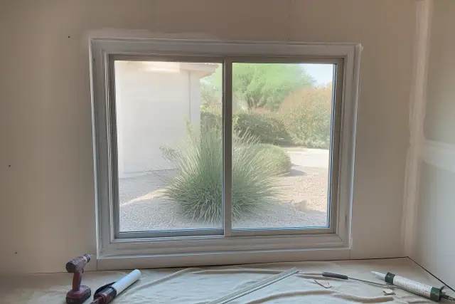 A newly installed window frame with sealant on a stucco wall at a job site in Queen Creek, AZ.