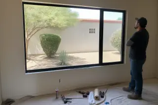 Technician inspecting a new window installation with tools on a drop cloth at a home in Phoenix, AZ.