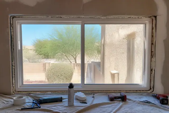 Double-slide window frame installation with tools on a drop cloth at a jobsite in Phoenix, AZ.
