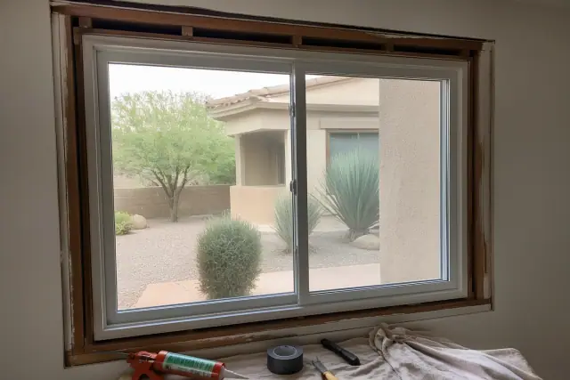 Vinyl window installation with tools on a drop cloth and desert landscaping visible outside in Phoenix, AZ.