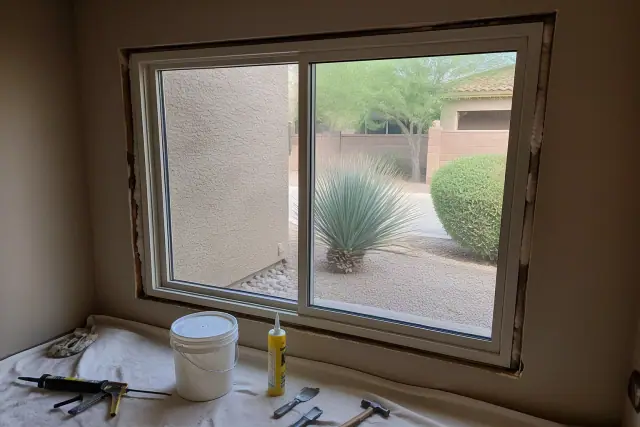 A window frame being installed with tools and sealing materials on a drop cloth at a worksite in Phoenix, AZ.