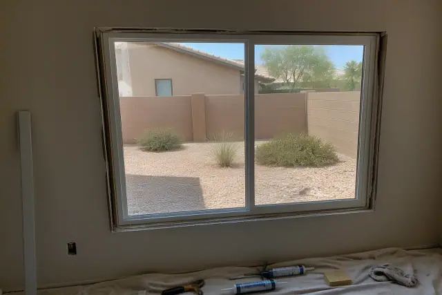 A new window frame installation at a residential job site in Phoenix, AZ, with tools visible on a drop cloth.