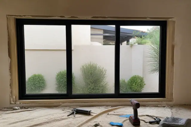 A custom window frame installation on a jobsite in Phoenix, AZ with tools and desert landscaping visible outside.