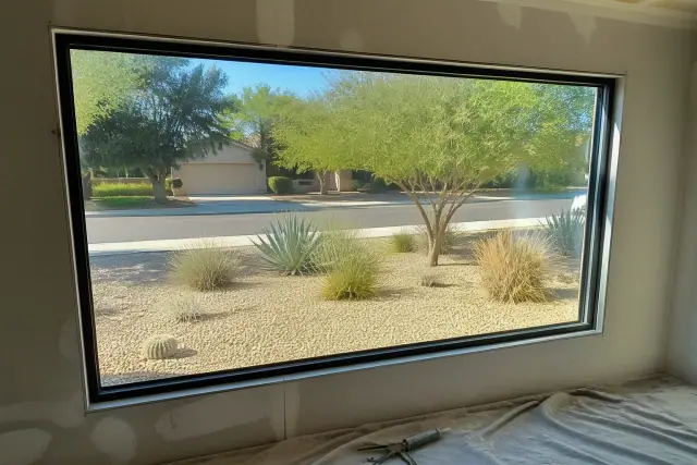A picture window frame installed in a stucco wall with interior silicone sealant in a home in Tempe, AZ.