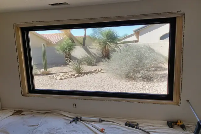 Window frame installation with sealing tools on a drop cloth in a Chandler, AZ home.