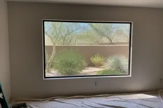 Finished picture window frame installed in a stucco home in Phoenix, AZ with desert landscaping visible outside.