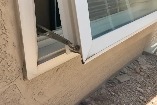 Close-up of a sagging window hinge and uneven sash reveal on a stucco wall at a jobsite in Phoenix, AZ.