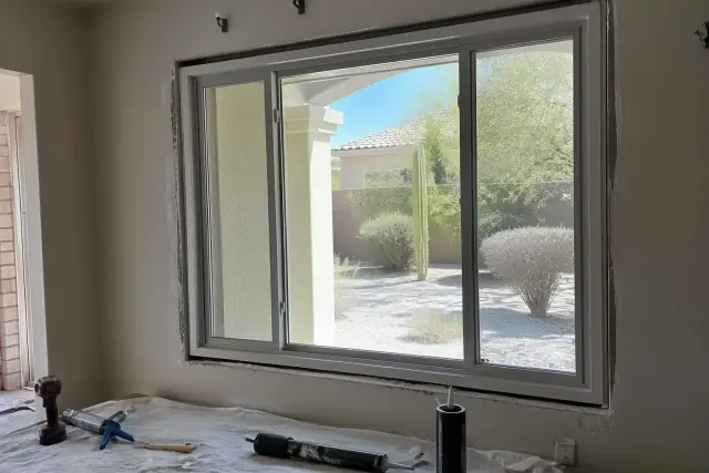New sliding window frame installation on a jobsite in Chandler, AZ with tools and materials on a drop cloth.