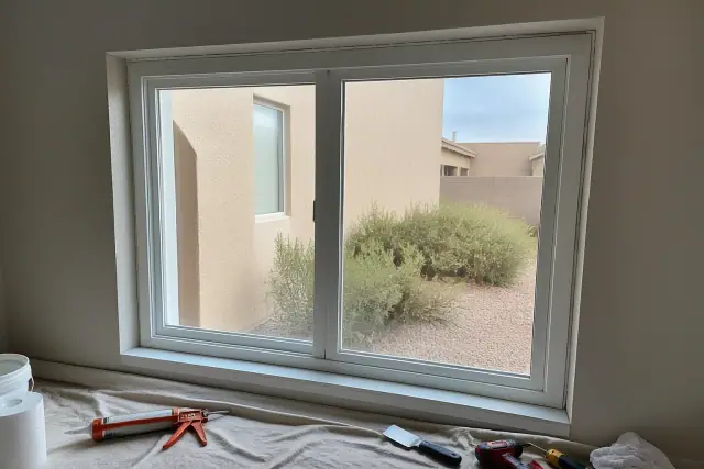 Sliding window frame installation with fresh sealant in a Queen Creek, AZ home.