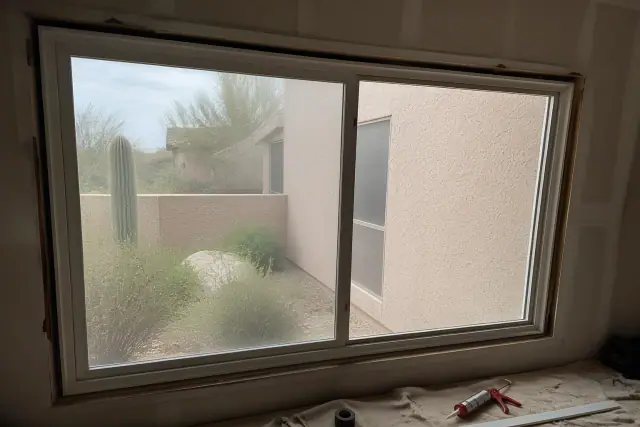 Sliding window frame installation in a Scottsdale, AZ home with tools and materials on a drop cloth.