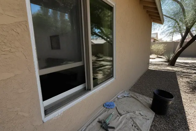 Sliding window installation at a beige stucco home in Tempe, AZ, featuring a new glass sash and fresh exterior caulking.