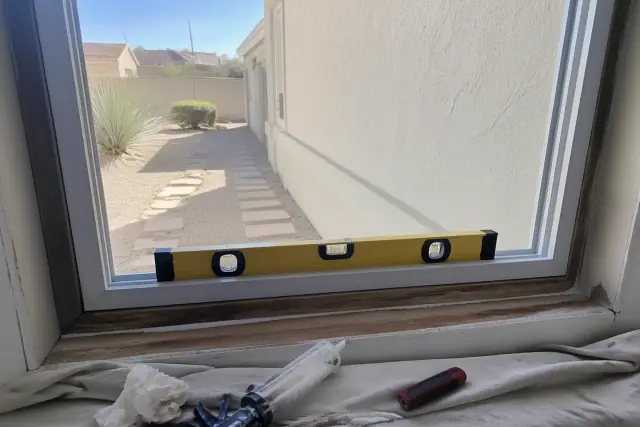 Sliding window installation with a spirit level and sealant on a residential job site in Surprise, AZ.