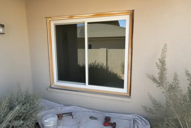 Sliding window installation with sealant and tools on a stucco wall in Glendale, AZ.