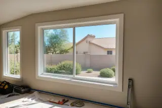 Sliding window frame installed in a stucco wall with tools on a drop cloth in a Phoenix, AZ home.