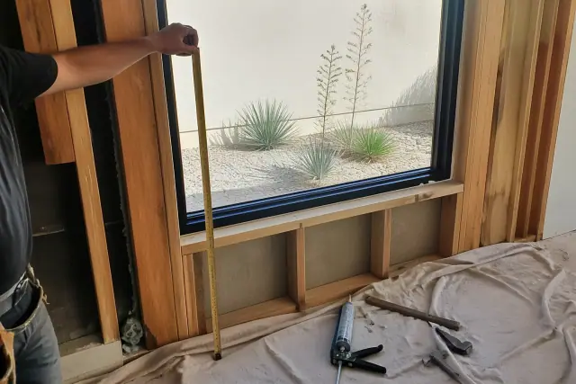 Contractor using a tape measure to take a three-point rough opening measurement at a Phoenix, AZ jobsite.