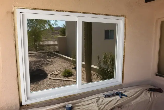 New vinyl window installation in a stucco home in Mesa, AZ, with tools on a drop cloth.
