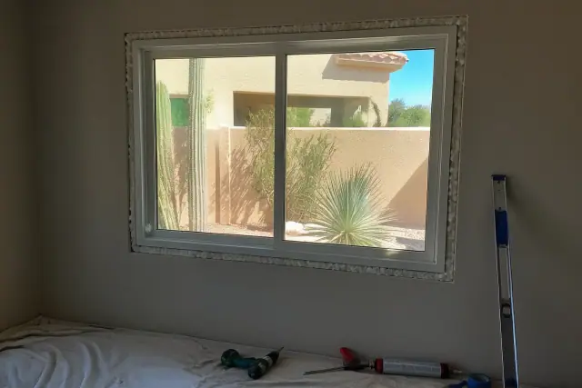 New vinyl window installation in a stucco home in Phoenix, AZ, with tools and materials on a drop cloth.