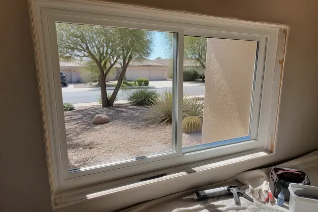 New vinyl window frame installed in a stucco home with sealant in Peoria, AZ.