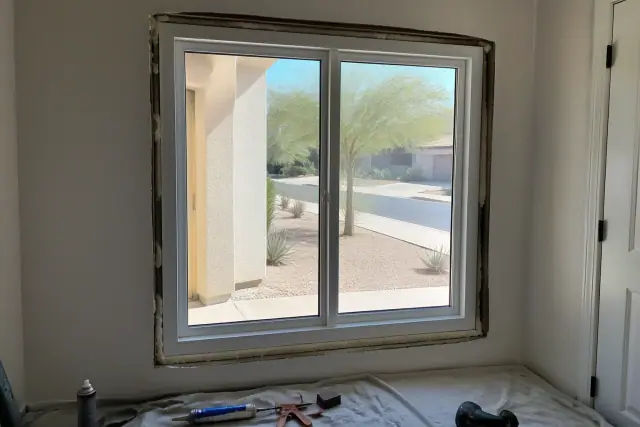 Vinyl window frame being installed in a stucco home with a view of a xeriscaped yard in Chandler, AZ.