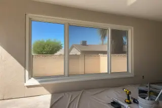 Newly installed vinyl window frame in a stucco wall under bright desert sun in Phoenix, AZ.