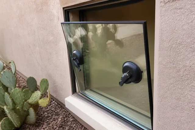 A replacement glass insert with safety suction tools being installed in a window frame at a home in Mesa, AZ.