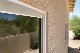 Caulked window frame perimeter on a beige stucco wall at a home in Phoenix, AZ.