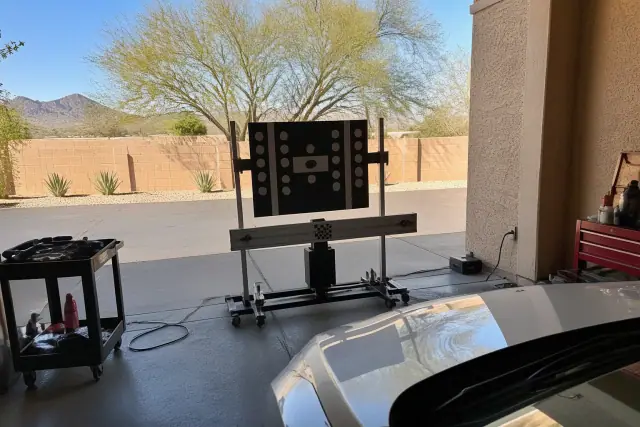 Digital calibration target stand positioned in front of a vehicle during ADAS calibration in a Phoenix, AZ service bay.