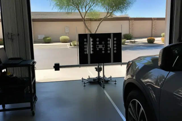 ADAS calibration target stand positioned in front of a vehicle at an auto service bay in Chandler, AZ.