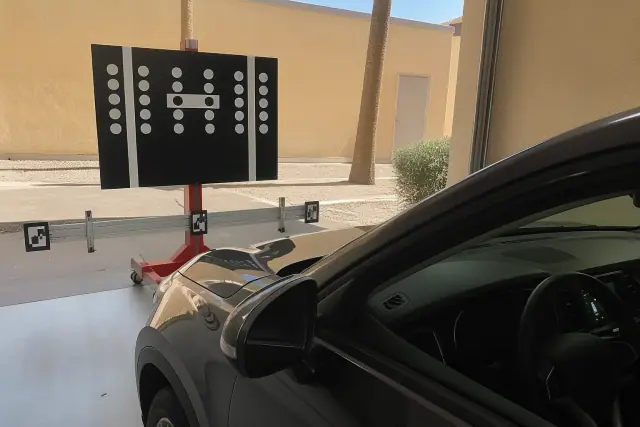 Digital ADAS calibration target stand positioned in front of a vehicle at a service bay in Phoenix, AZ.