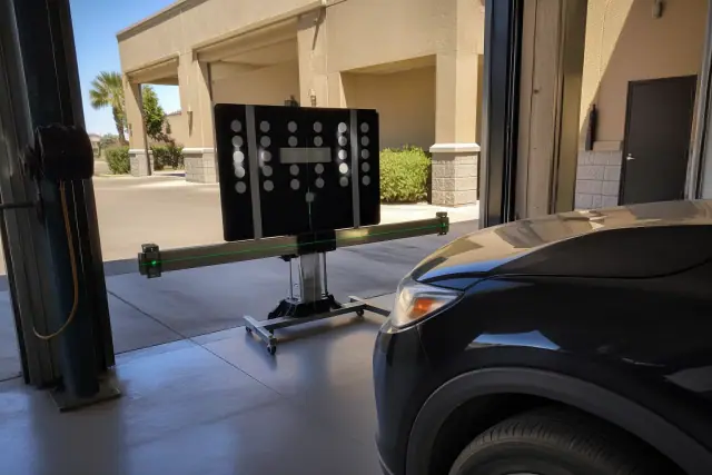 ADAS calibration target stand aligned in front of a vehicle at a service bay in Mesa, AZ.