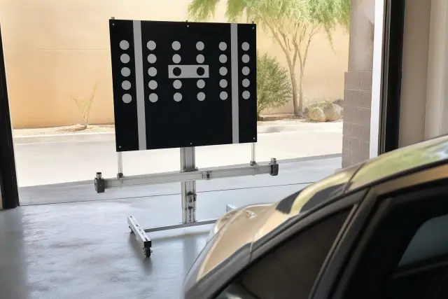 Digital ADAS calibration target stand in front of a vehicle at a service bay in Glendale, AZ.