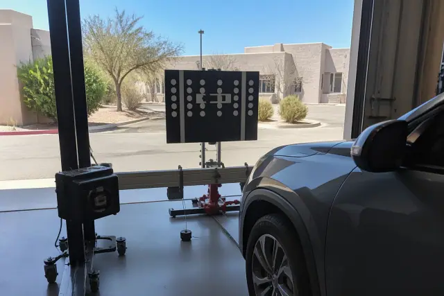 ADAS calibration tools and a digital target stand set up in front of a vehicle at a service bay in Tempe, AZ.