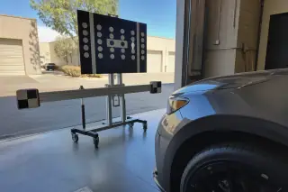 Digital ADAS calibration target stand positioned in front of a vehicle in a Phoenix, AZ service bay.