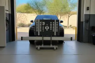 Digital calibration target stand set up in front of a car inside a Phoenix, AZ service bay.