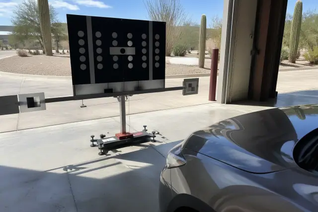 ADAS camera and calibration target setup in front of a vehicle in a Phoenix, AZ service bay.