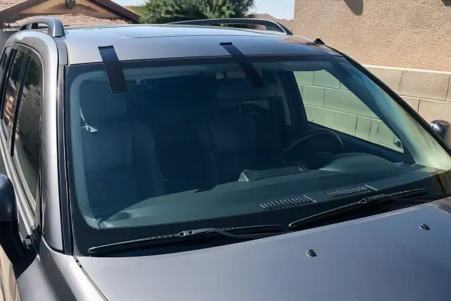 Newly installed vehicle windshield held in place by retention tape on a sunny day in Glendale, AZ.