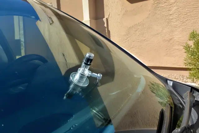 Close-up of a resin injector tool repairing a windshield star break on a vehicle in Phoenix, AZ.