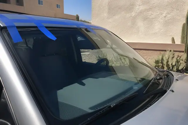 A car with a newly installed windshield held by retention tape at a jobsite in Chandler, AZ.