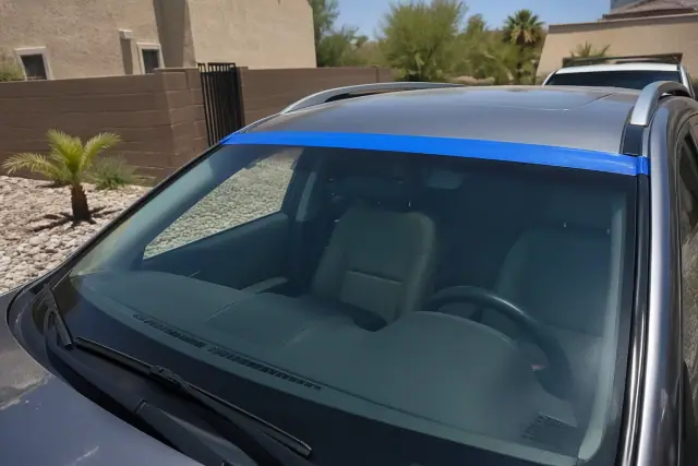 Newly installed windshield with retention tape on a car in a residential driveway in Peoria, AZ.