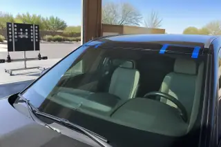 Car windshield with retention tape parked in a sunny service bay in Phoenix, AZ.