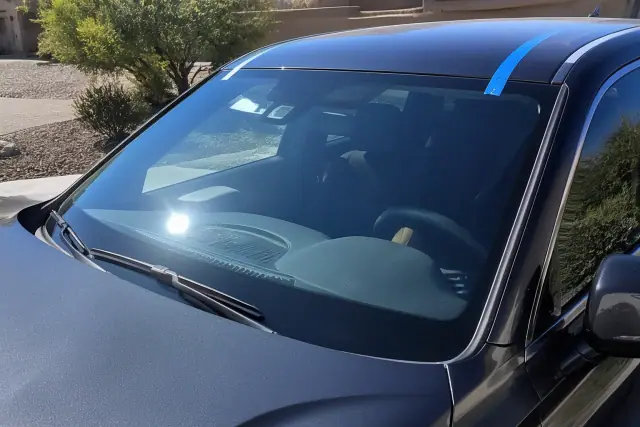 Newly installed car windshield with professional retention tape on a vehicle in a Phoenix, AZ driveway.